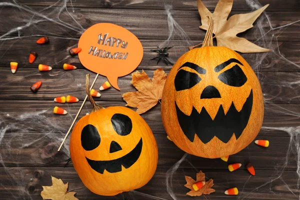 Calabazas naranjas con texto Feliz Halloween y dulces en madera — Foto de Stock