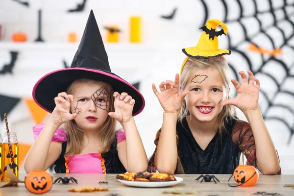 Chicas jóvenes en disfraces de Halloween sentados junto a la mesa —  Fotos de Stock