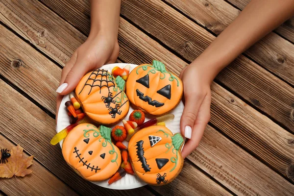 Halloween gingerbread cookies with candies in female hands on br — Stock Photo, Image