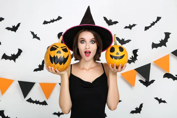 Gelukkige jonge vrouw in zwart kostuum houden Halloween pompoenen op — Stockfoto