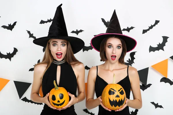 Dvě mladé ženy v černých kostýmech, které drží Halloween dýně — Stock fotografie