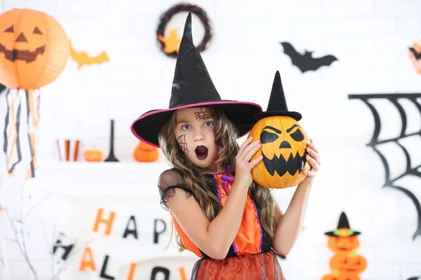 Hermosa chica en traje de Halloween celebración de calabaza con sombrero —  Fotos de Stock