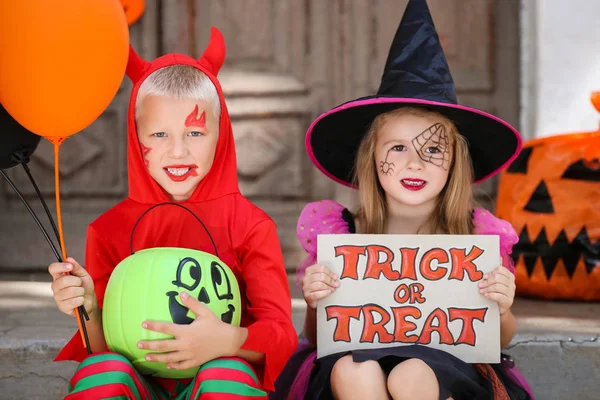 Giovane ragazza e ragazzo in costumi di Halloween seduto sul portico con p — Foto Stock