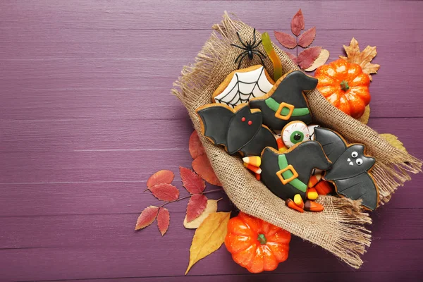 Halloween gingerbread cookies with dry leafs on purple wooden ta — Stock Photo, Image