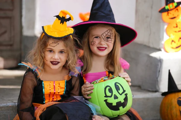 Chicas jóvenes en trajes de Halloween sentado en el porche con calabaza —  Fotos de Stock