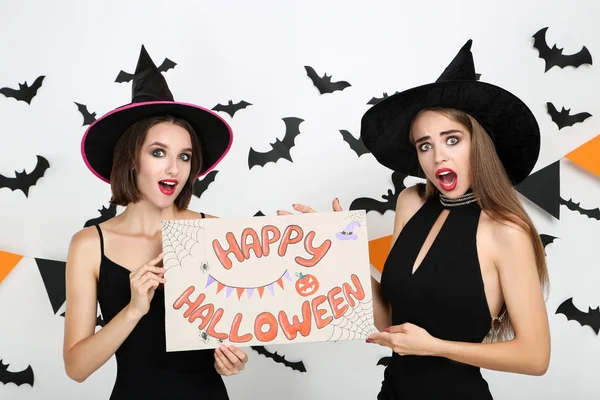 Twee jonge vrouwen in zwarte kostuums papier met tekst gelukkig — Stockfoto
