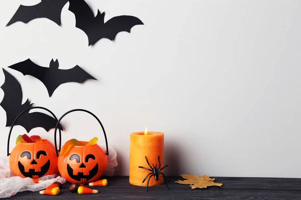Хеллоуїн цукерки з гарбузовими відрами, паперовими кажанами і свічками на — стокове фото