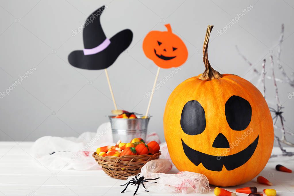 Halloween pumpkin with candies in basket and spider on grey back