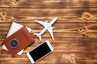 Pasaportu, akıllı telefonu ve kahverengi pusulası olan uçak modeli.