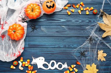 Cadılar Bayramı şekerleri ve mavi ahşap şeritte kuru yapraklar.