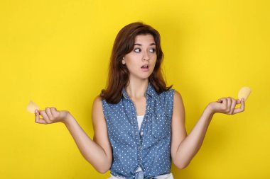 Sarı arka planda patates cipsi ile genç kadın