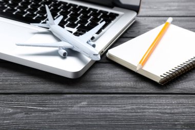 Laptop bilgisayarı ve siyah tahta üzerine not defteri olan uçak modeli. 