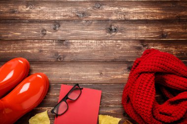 Lastik çizmeli yün eşarp, not defteri ve alnında sonbahar yaprakları