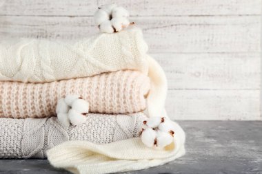 Beyaz ahşap sırtında pamuk çiçekli katlanmış süveterler.