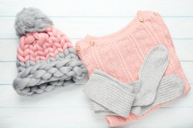 Ahşap masada şapka ve çorapla örülmüş süveter.