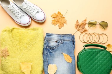 Güneş gözlüklü moda kıyafetleri ve bej sırt çantalı sonbahar yaprakları.