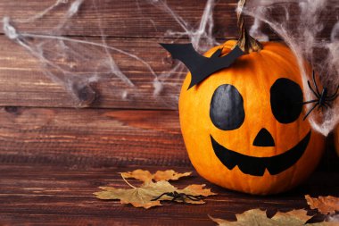 Kuru yapraklı cadılar bayramı balkabakları ve tahta sırtında kağıt yarasa.