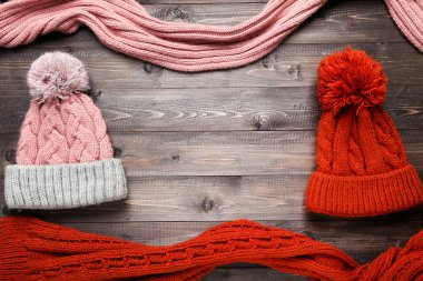 Kahverengi ahşap masada örülmüş şapka ve eşarplar.