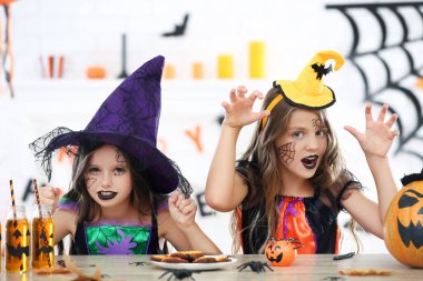 Cadılar Bayramı kostümlü iki güzel kız masanın yanında oturuyor.
