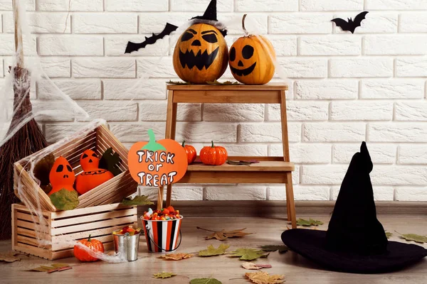 Halloween pumpor med godis, svart hatt och torra blad — Stockfoto