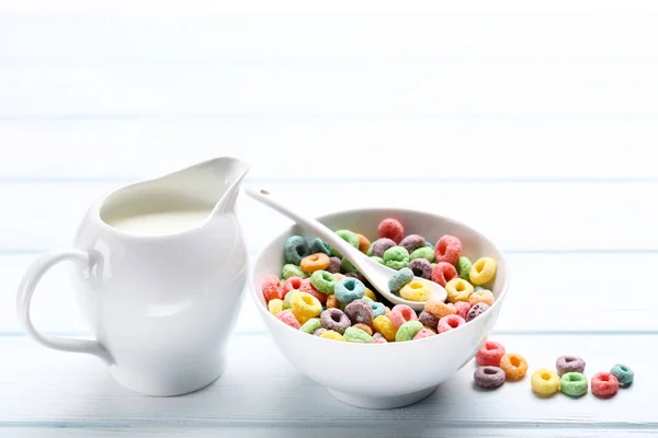 Цветные кукурузные кольца с молоком в банке на деревянном столе — стоковое фото