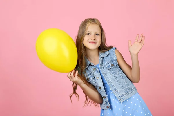 Niña bonita con globo de goma amarilla sobre fondo rosa — Foto de Stock