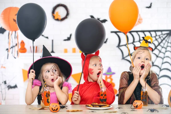 Giovani ragazze e ragazzo in costumi di Halloween con palloncini seduti — Foto Stock