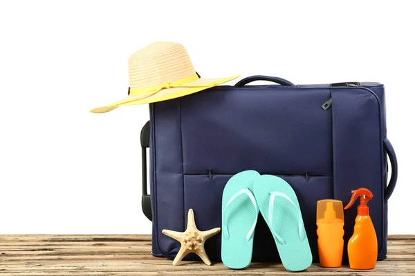 Üzerinde parmak arası terlik, şapka ve tahta üzerinde güneş kremi şişeleri olan mavi bavul. — Stok fotoğraf