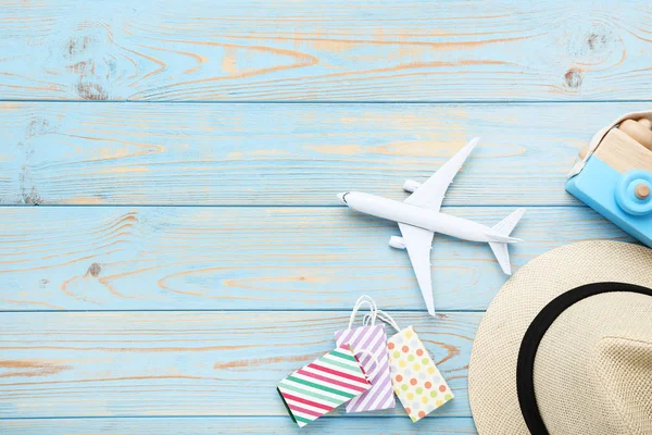 Modelo de avião com sacos de compras, chapéu e brinquedo de câmera em azul wo — Fotografia de Stock