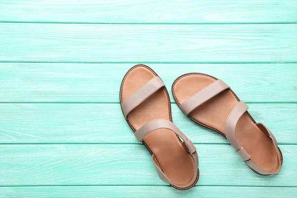 Vrouwelijke beige sandalen op munthouten tafel — Stockfoto