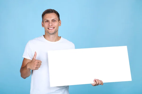 Junger Mann mit blankem Brett und Daumen nach oben auf blauem Hintergrund — Stockfoto