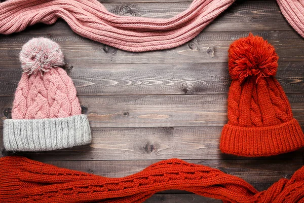 Knitted hats and scarfs on brown wooden table — Stock Photo, Image