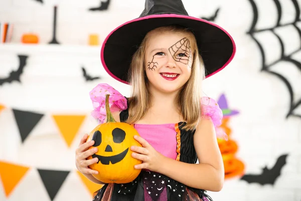 Jong meisje in Halloween kostuum met oranje pompoen — Stockfoto