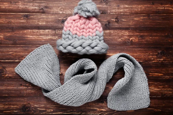 Gorro y bufanda de punto sobre mesa de madera marrón — Foto de Stock