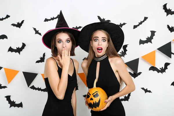 Két fiatal nő fekete jelmezben kezében halloween tök — Stock Fotó