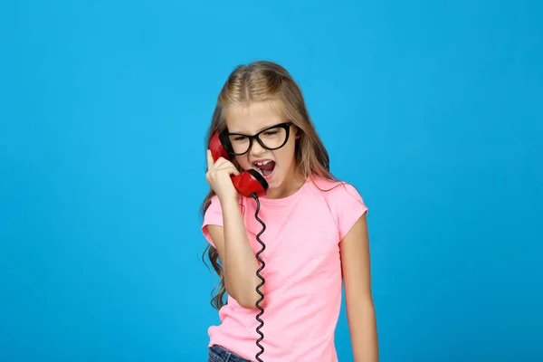 Niña gritando en el teléfono sobre fondo azul — Foto de Stock