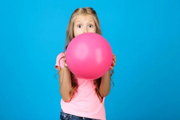 Pretty little girl dmuchanie różowy balon na niebieskim tle — Zdjęcie stockowe