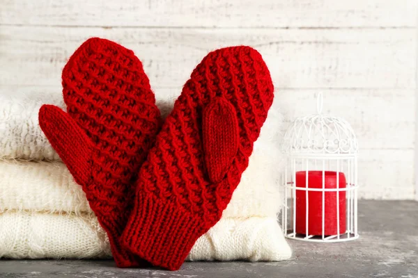Geplooide gebreide truien met handschoenen en kaarsen op grijs t — Stockfoto