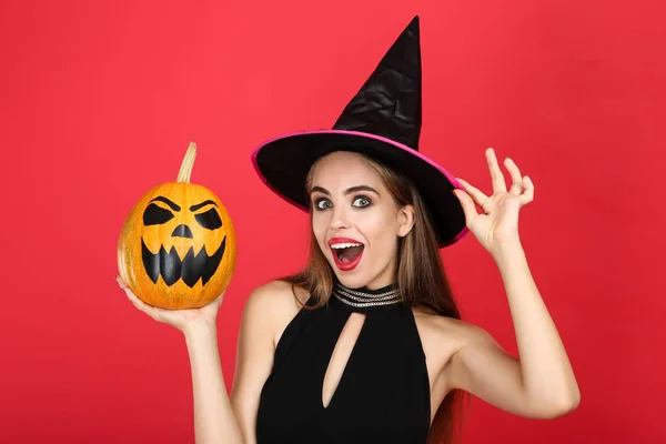 Mulher bonita em traje preto segurando abóbora halloween em re — Fotografia de Stock