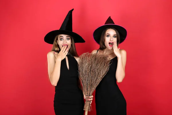 Dvě mladé ženy v černých Halloweenských kostýmech s smetákem na červenou ba — Stock fotografie