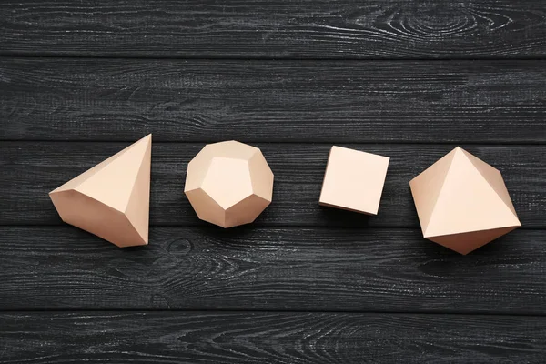 Paper geometric figures on black wooden table — Stock Image Paper geometric figures on black wooden table Royalty Free Stock Photos
