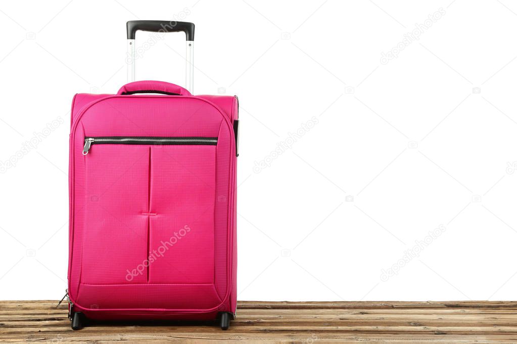 Pink suitcase on wooden table