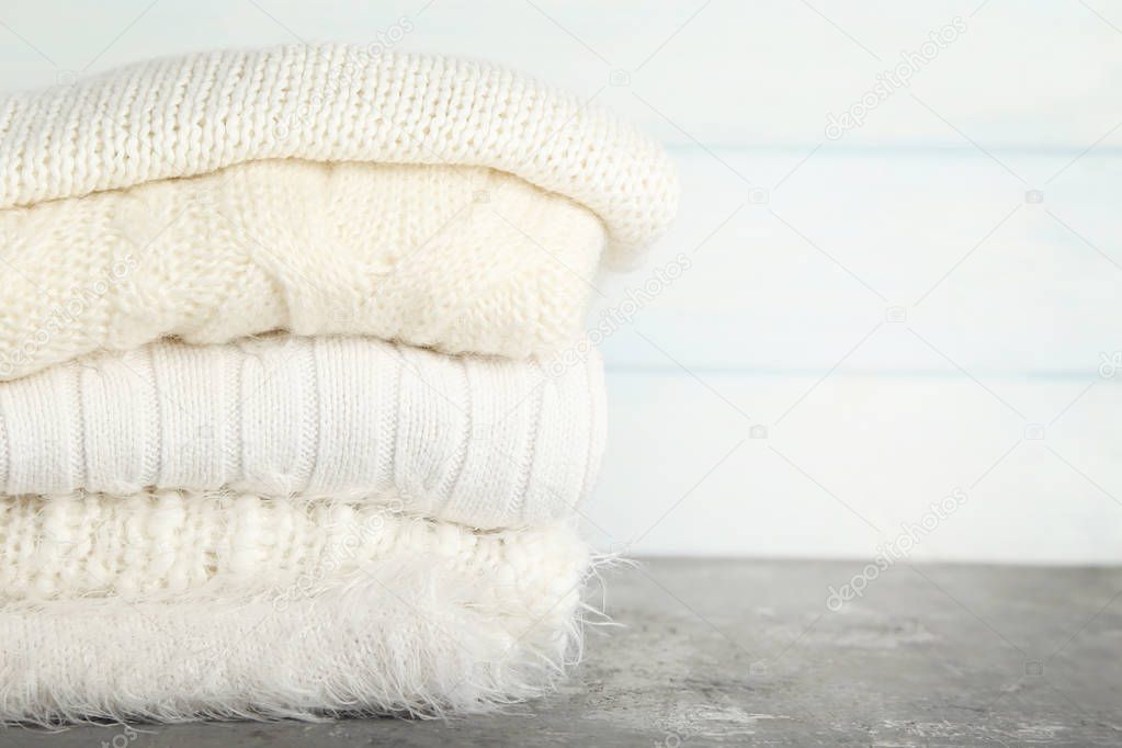 Folded knitted sweaters on wooden background