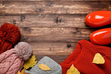 Şapkalı yün süveter, lastik çizmeler ve kahverengi yapraklı sonbahar yaprakları. 