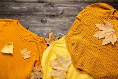 Kahverengi ahşap masada sonbahar yapraklı yün kazaklar.