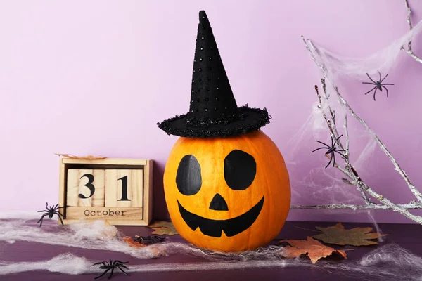 Хэллоуинская тыква с деревянным календарем, веткой деревьев и пауком — стоковое фото