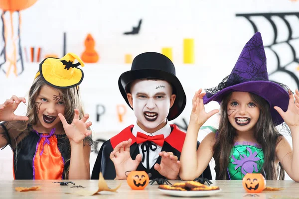 Две девочки и мальчик в костюмах Хэллоуина сидят рядом — стоковое фото