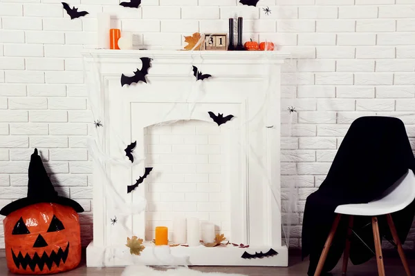 Halloween decorations on white fireplace with orange pumpkin and