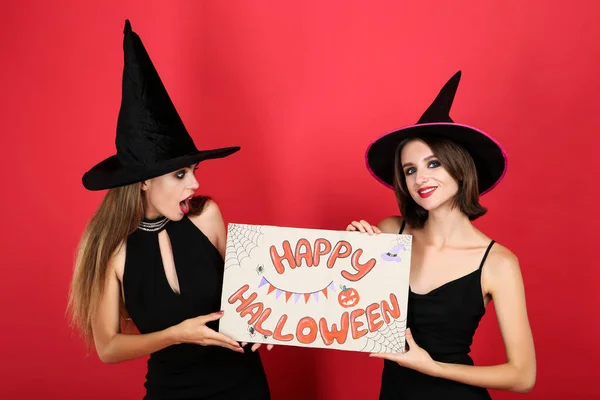 Two young women in black costumes holding paper with text Happy — Stock Photo, Image