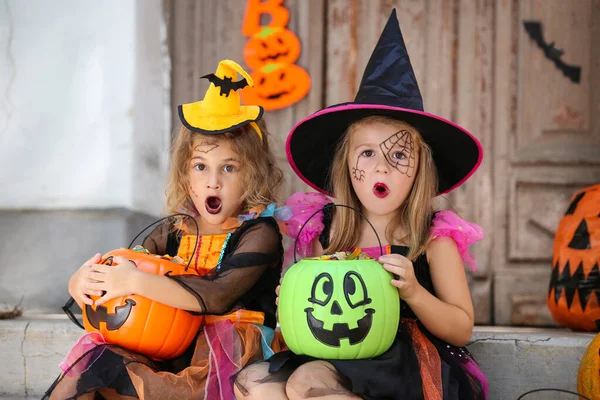 Young girls in halloween costumes sitting on porch with pumpkin — Stock Photo, Image